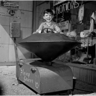 Boy in toy ride outside store Poster Print (18 x 24)